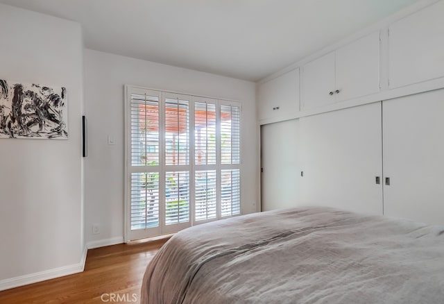 bedroom with baseboards, light wood-style floors, and a closet
