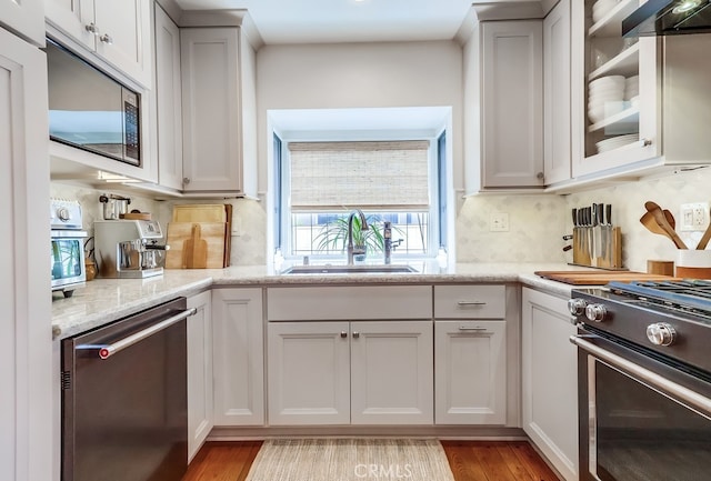 kitchen featuring backsplash, light wood-style floors, stainless steel appliances, and a sink
