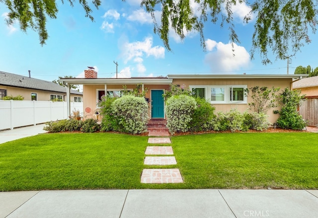 ranch-style home featuring a chimney, a front yard, and fence