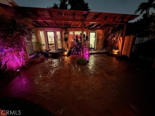 patio at night featuring outdoor dining space and a pergola