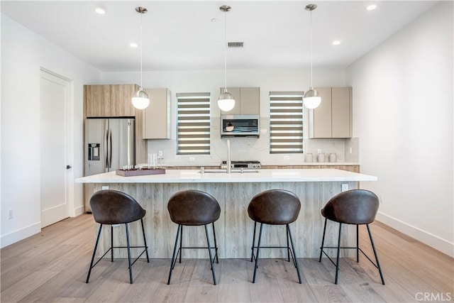 kitchen with light countertops, stainless steel appliances, light wood-style flooring, and visible vents