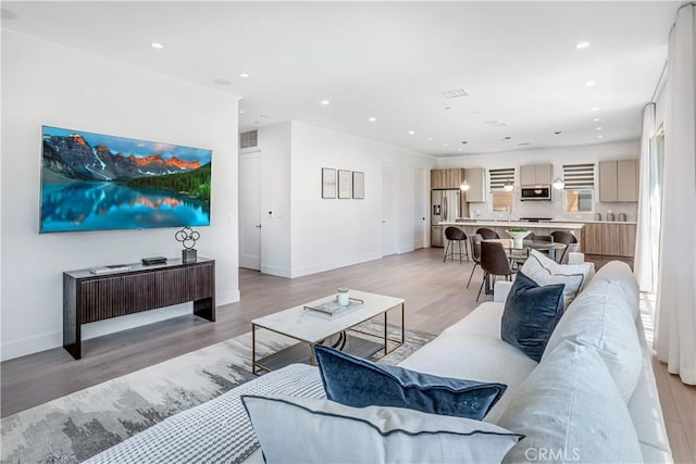 living room featuring baseboards, recessed lighting, light wood finished floors, and visible vents