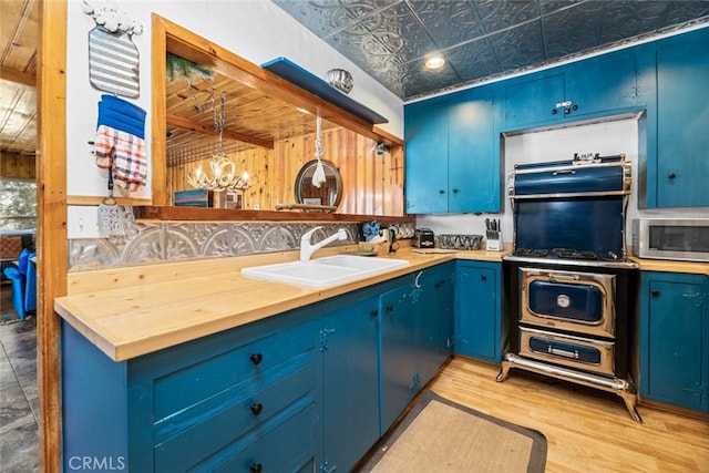 kitchen featuring stainless steel microwave, an ornate ceiling, a sink, and blue cabinetry