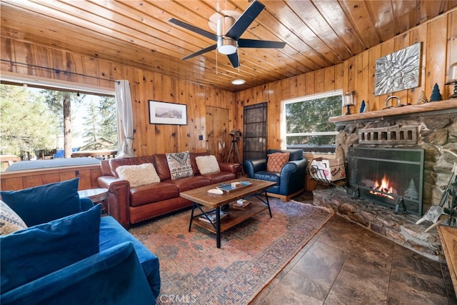 living area featuring a ceiling fan, wooden ceiling, stone finish flooring, wood walls, and a fireplace