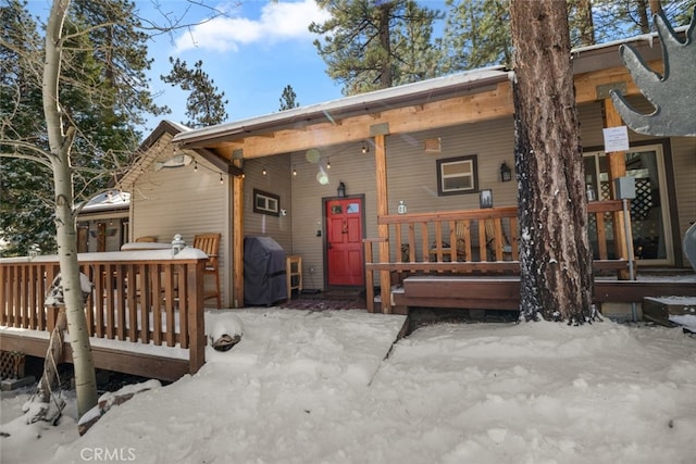 snow covered rear of property featuring a porch