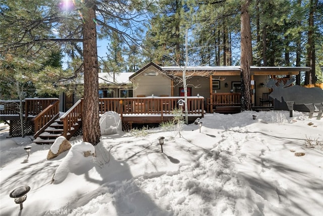 snow covered back of property with a deck