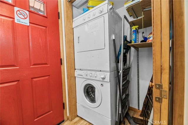 clothes washing area with laundry area, stacked washer and clothes dryer, and light wood-style floors