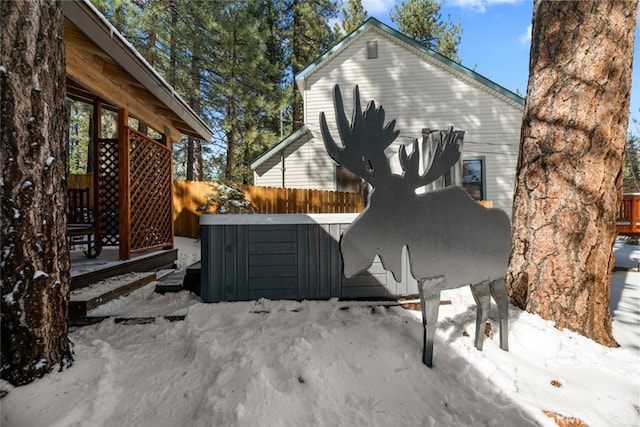 snow covered property featuring fence and a jacuzzi