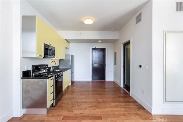 kitchen with appliances with stainless steel finishes, visible vents, baseboards, and light wood-type flooring