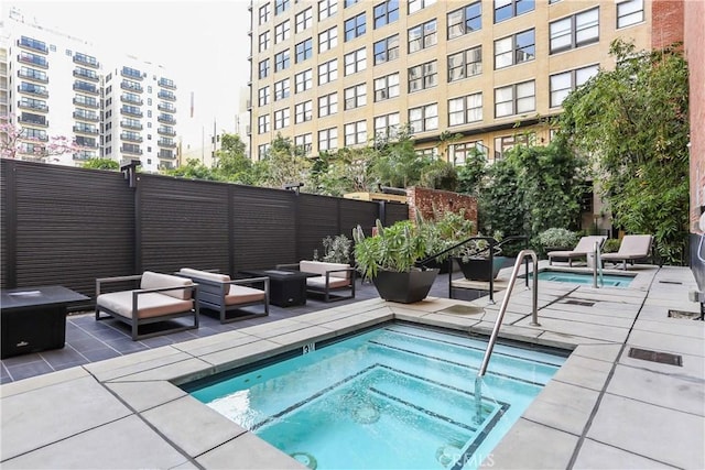 view of swimming pool featuring a hot tub, a swimming pool, an outdoor hangout area, a patio area, and a fenced backyard