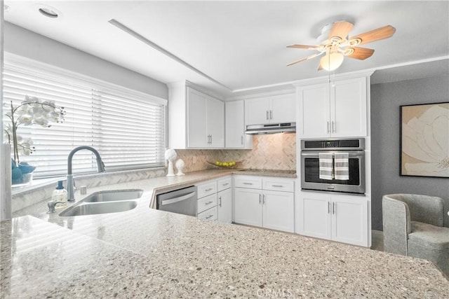 kitchen with a sink, under cabinet range hood, white cabinetry, a ceiling fan, and appliances with stainless steel finishes