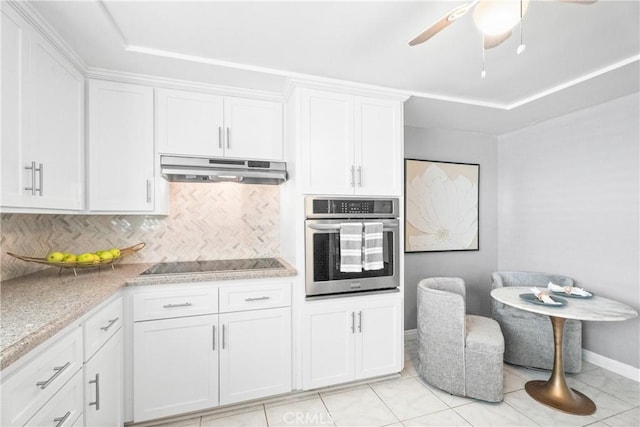 kitchen featuring stainless steel oven, under cabinet range hood, white cabinets, black electric cooktop, and baseboards