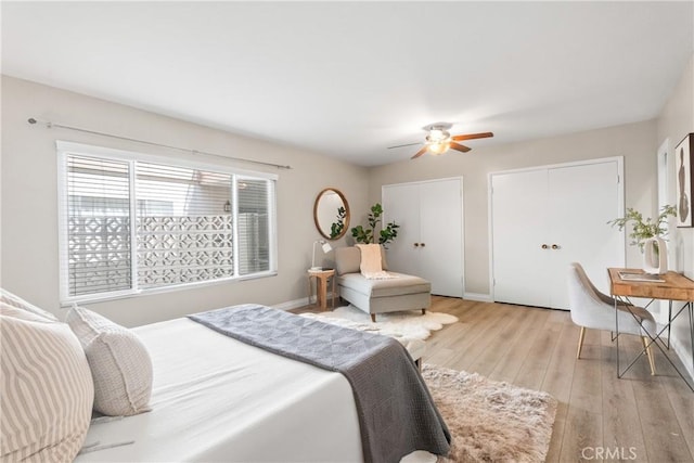bedroom with light wood finished floors, baseboards, a ceiling fan, and multiple closets