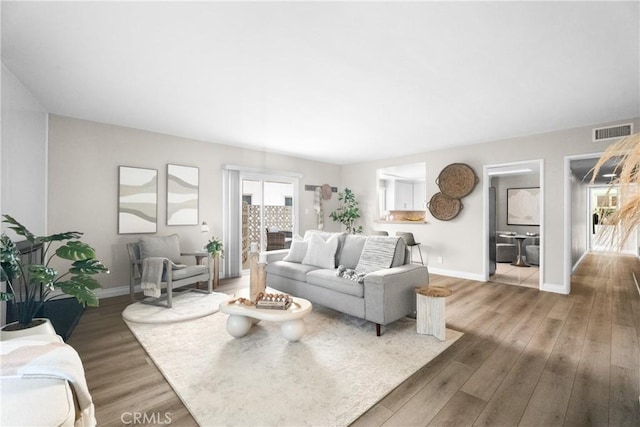 living area featuring visible vents, wood finished floors, and baseboards