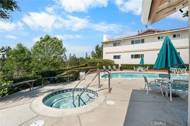 community pool with a patio and a hot tub