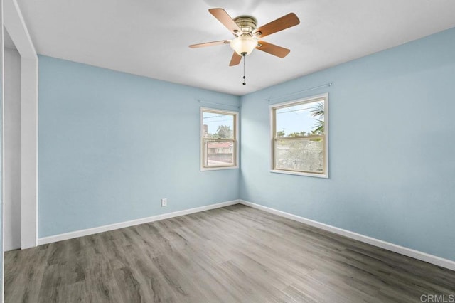 unfurnished room with a ceiling fan, wood finished floors, and baseboards