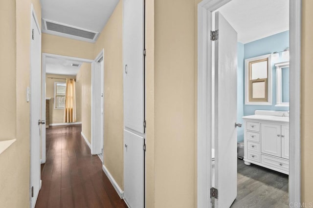 hallway with baseboards, visible vents, and dark wood-type flooring