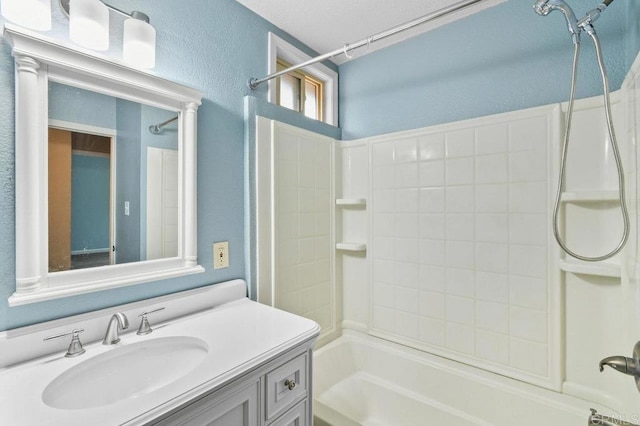 full bathroom with shower / bath combination, vanity, and a textured wall