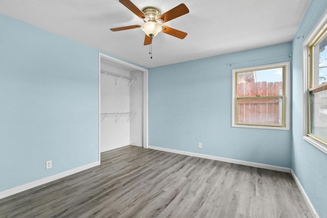 unfurnished bedroom with a closet, a ceiling fan, wood finished floors, and baseboards