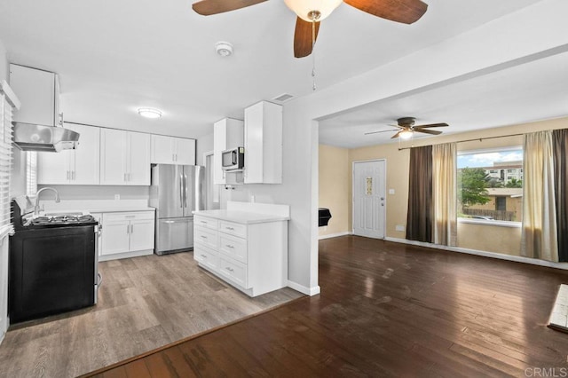 kitchen with light wood finished floors, white cabinets, ceiling fan, light countertops, and appliances with stainless steel finishes