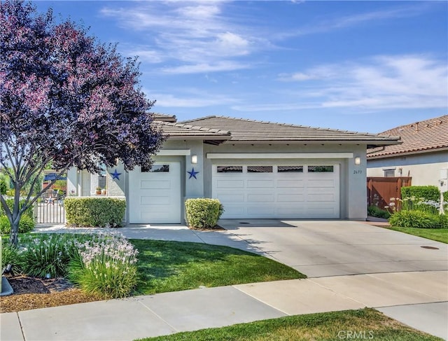 view of front facade with concrete driveway, stucco siding, an attached garage, and fence