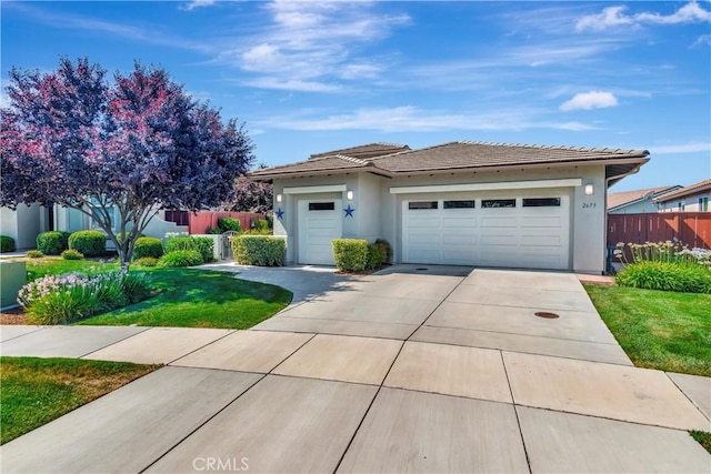 view of front of home featuring fence, a garage, stucco siding, a tile roof, and concrete driveway