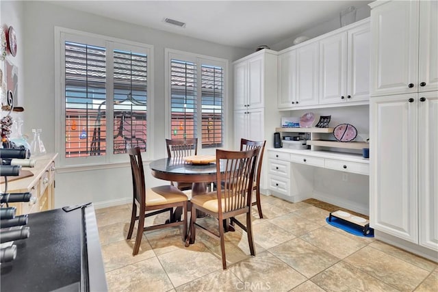 dining area with baseboards, built in desk, visible vents, and light tile patterned flooring