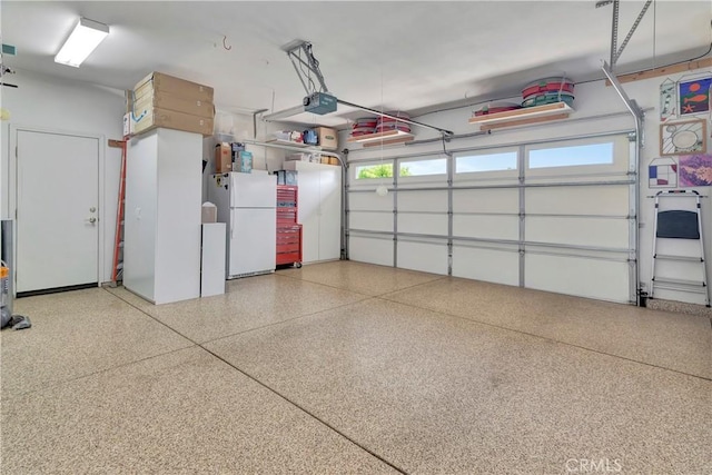 garage featuring freestanding refrigerator and a garage door opener