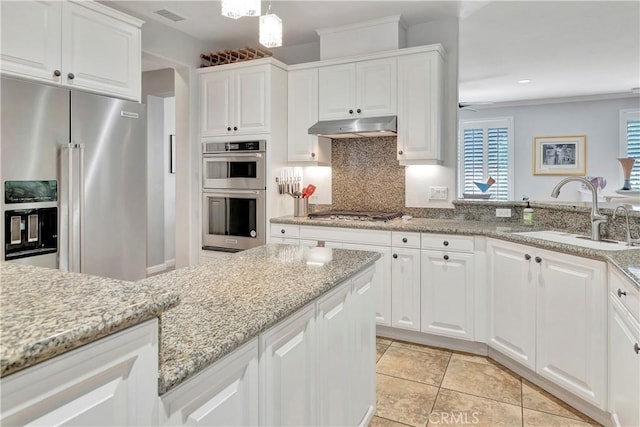 kitchen with light stone countertops, under cabinet range hood, a sink, stainless steel appliances, and white cabinets