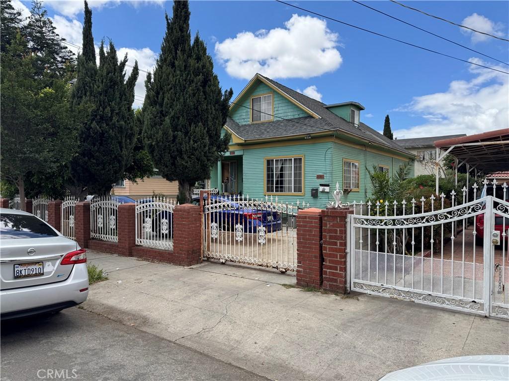 view of front of property featuring a fenced front yard, a shingled roof, and a gate