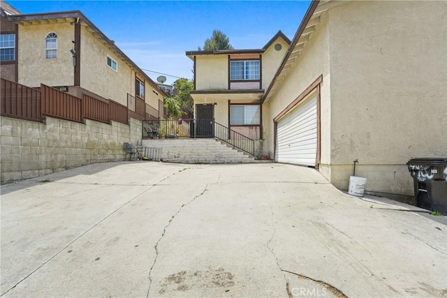 49604962 Gambier St, Los Angeles, CA 90032 - rear view of property featuring stucco siding, driveway, an attached garage, and fence