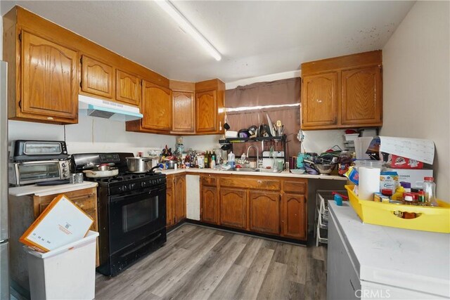 49604962 Gambier St, Los Angeles, CA 90032 - kitchen with black gas range oven, under cabinet range hood, a sink, and brown cabinetry