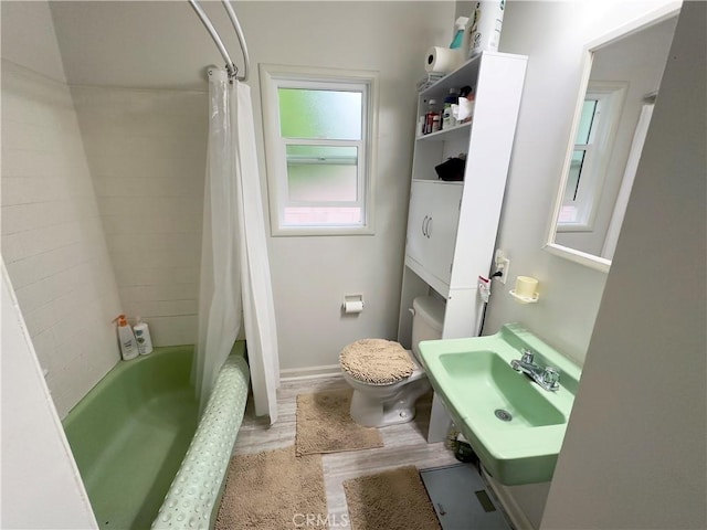 full bathroom featuring a sink, shower / bath combo, toilet, and wood finished floors