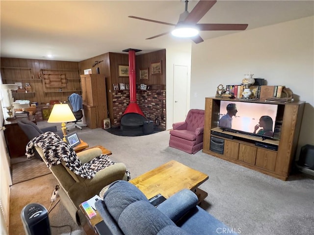 living area with a wood stove, carpet floors, and a ceiling fan