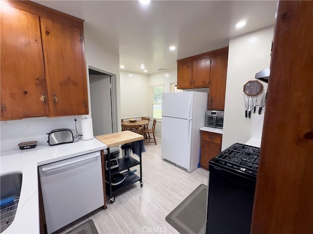 kitchen featuring freestanding refrigerator, black range with gas cooktop, stainless steel dishwasher, light countertops, and light wood-type flooring