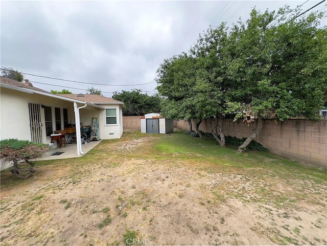 view of yard featuring a patio area, an outdoor structure, a fenced backyard, and a shed