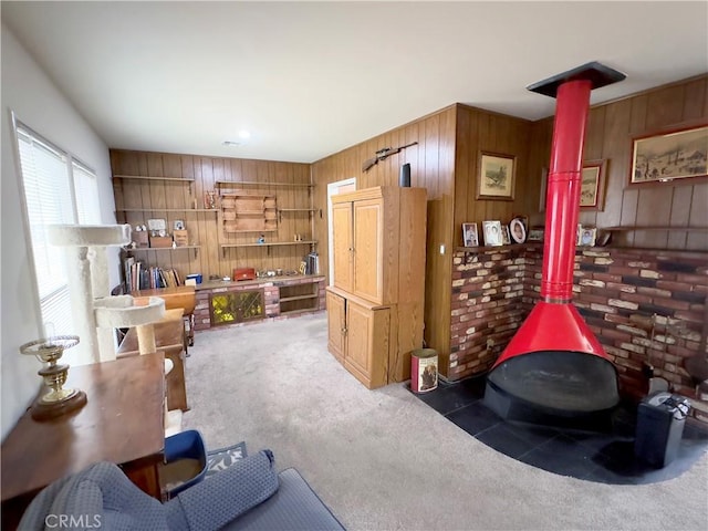 interior space with a wood stove, wood walls, and carpet floors