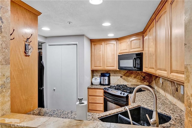 kitchen featuring black appliances, a sink, light stone countertops, backsplash, and light brown cabinets