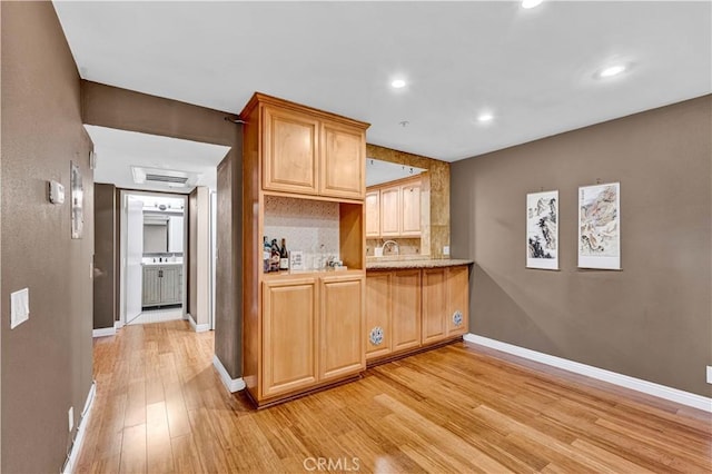 kitchen with light wood-type flooring, light countertops, recessed lighting, baseboards, and decorative backsplash