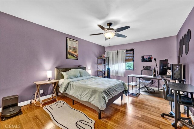 bedroom with a desk, wood finished floors, baseboards, and a ceiling fan
