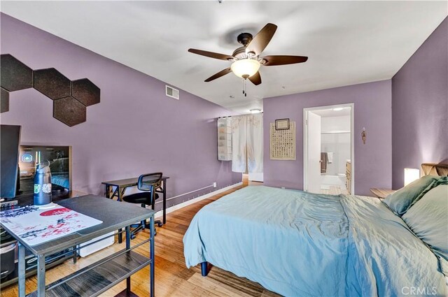 bedroom with wood finished floors, a ceiling fan, connected bathroom, and baseboards