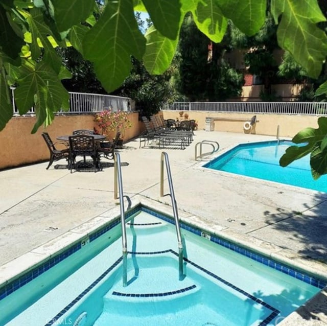 community pool featuring fence and a patio area