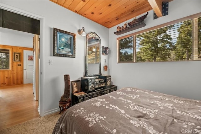 carpeted bedroom with baseboards, wooden walls, and wood ceiling