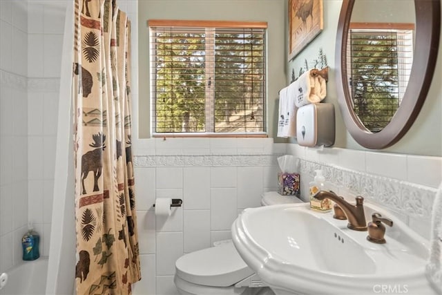 bathroom featuring a sink, toilet, a wealth of natural light, and tile walls