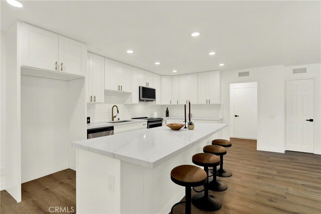 21011 N Hampton Way, Lake Forest, CA 92630 - kitchen with appliances with stainless steel finishes, a kitchen bar, a sink, wood finished floors, and white cabinets