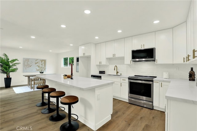 21011 N Hampton Way, Lake Forest, CA 92630 - kitchen featuring stainless steel appliances, a sink, light wood-style flooring, a kitchen island, and white cabinetry