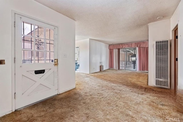 foyer featuring a textured ceiling, carpet flooring, and a heating unit