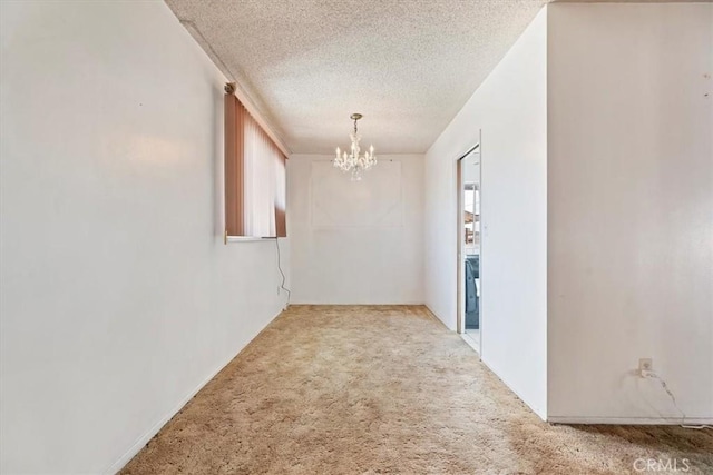 unfurnished room featuring a chandelier, a textured ceiling, and carpet flooring