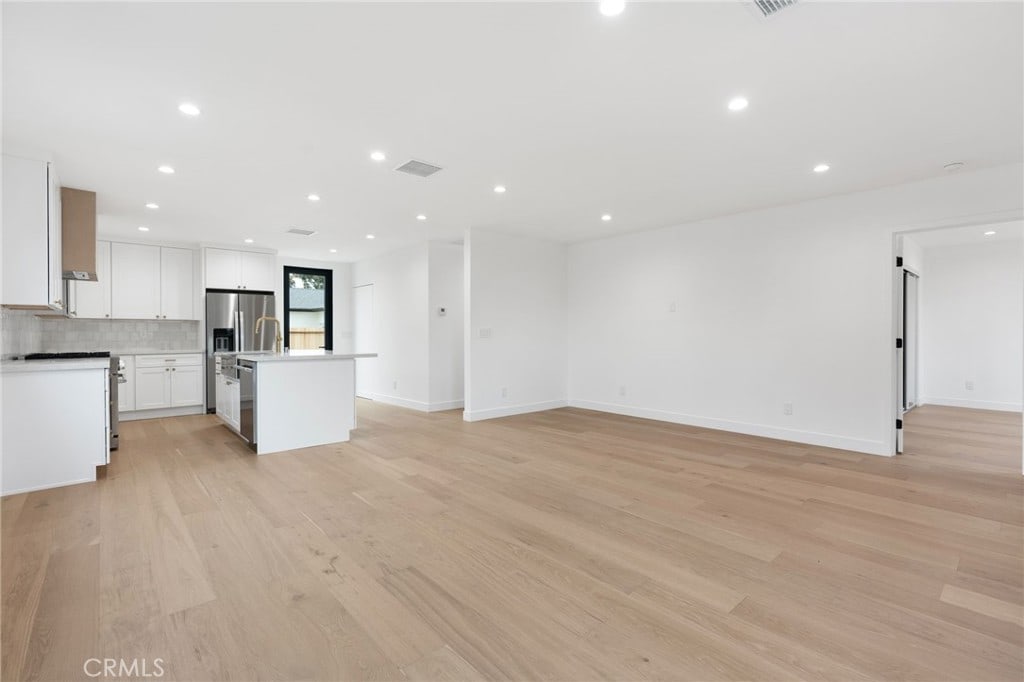 unfurnished living room featuring light wood finished floors, baseboards, visible vents, and recessed lighting