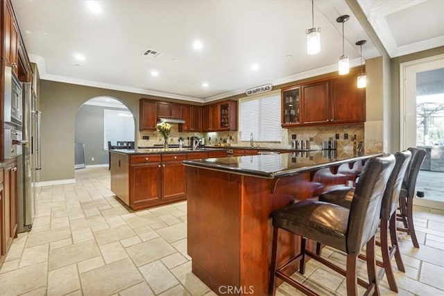 200 Cross Rail Ln, Norco, CA 92860 - kitchen featuring a peninsula, dark countertops, arched walkways, ornamental molding, and decorative backsplash